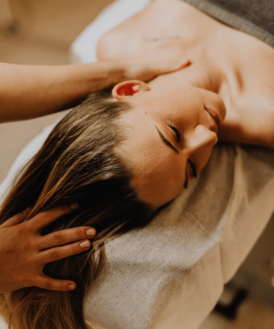 Hands-of-a-masseuse-massaging-the-head-and-neck-of-a-woman-lying-on-her-back-lying-on-a-massage-table-in-a-comfortable-environment